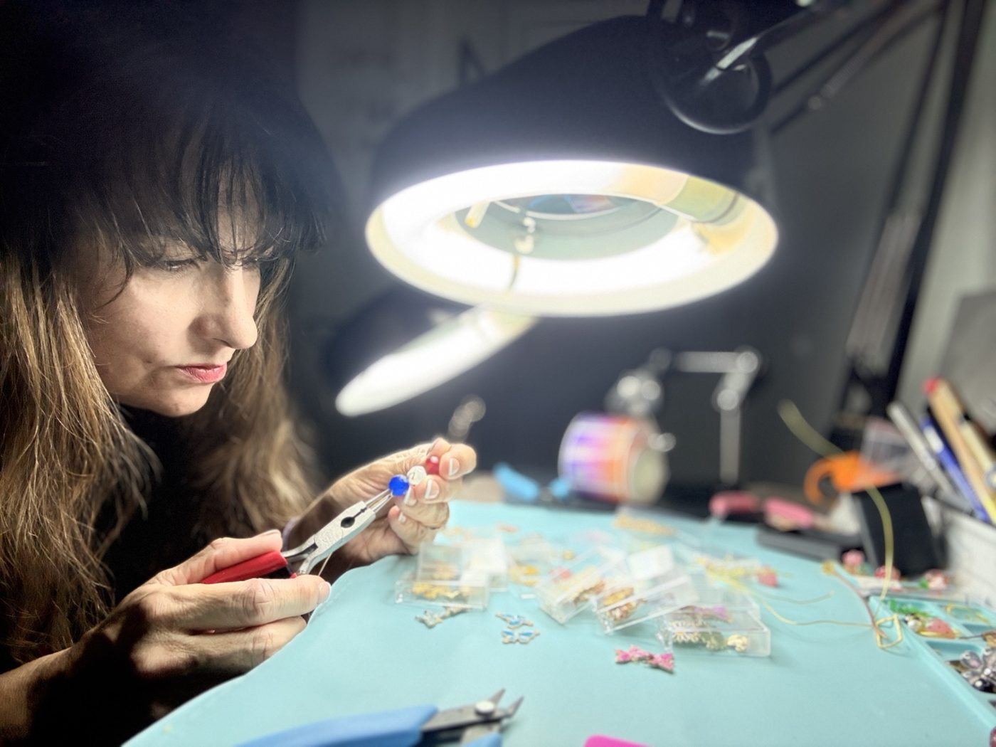 Carmen making jewelry at her workbench